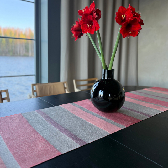 Löpare i linne i randigt med olika färger av blått med växter och ljus som står på löparen