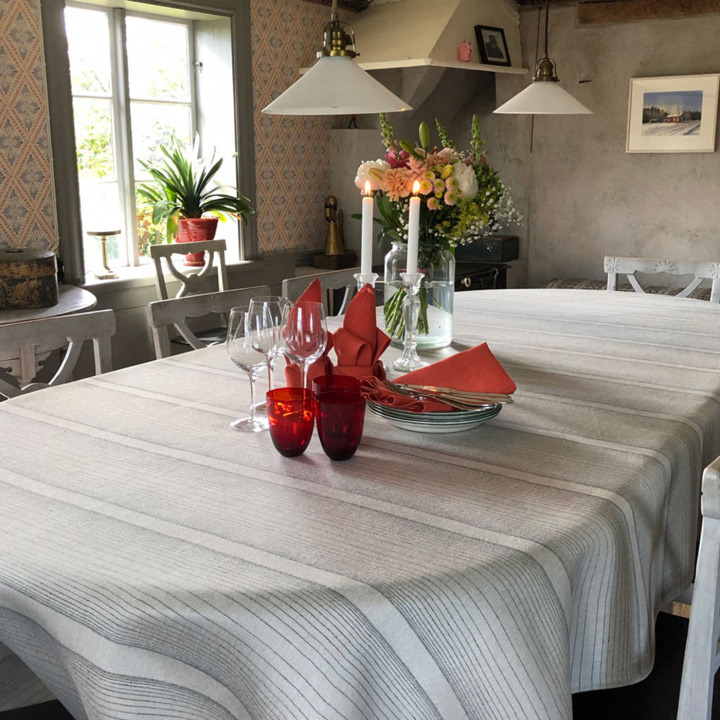 Linneduk i vita och grå ränder som ligger på ett dukat matbord