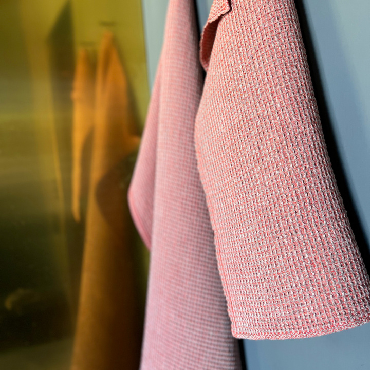 Glashandduk i linne från Växbo Lin i gult som ligger på kanten av ett badkar i ett badrum